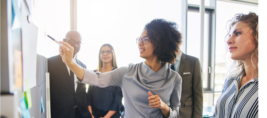 Woman in small group pointing to something on a whiteboard